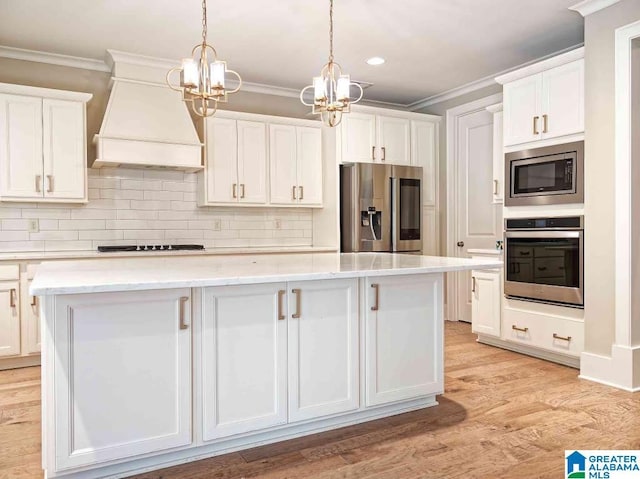 kitchen with white cabinetry, appliances with stainless steel finishes, custom range hood, and a kitchen island