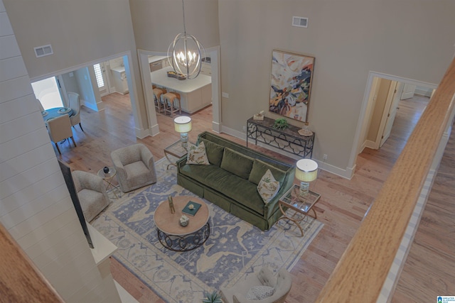 living room with an inviting chandelier, light hardwood / wood-style floors, and a high ceiling