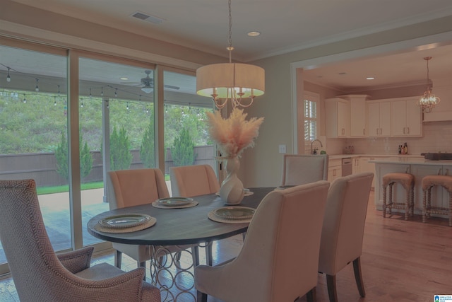 dining area featuring ornamental molding, ceiling fan with notable chandelier, and light wood-type flooring