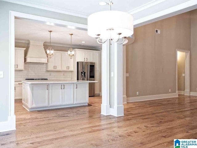 kitchen featuring white cabinetry, a notable chandelier, custom range hood, and a kitchen island