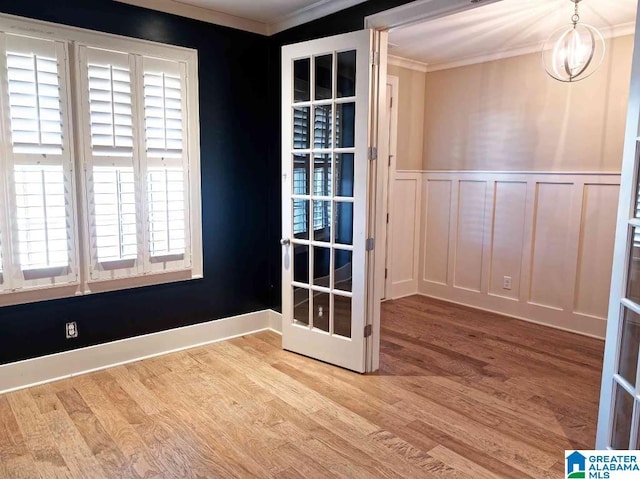 empty room with french doors, crown molding, and light hardwood / wood-style flooring