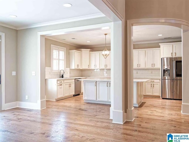 kitchen featuring white cabinetry, decorative light fixtures, light hardwood / wood-style floors, and appliances with stainless steel finishes