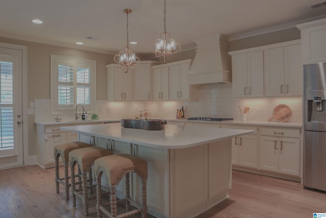 kitchen with white cabinetry, a center island, appliances with stainless steel finishes, and premium range hood