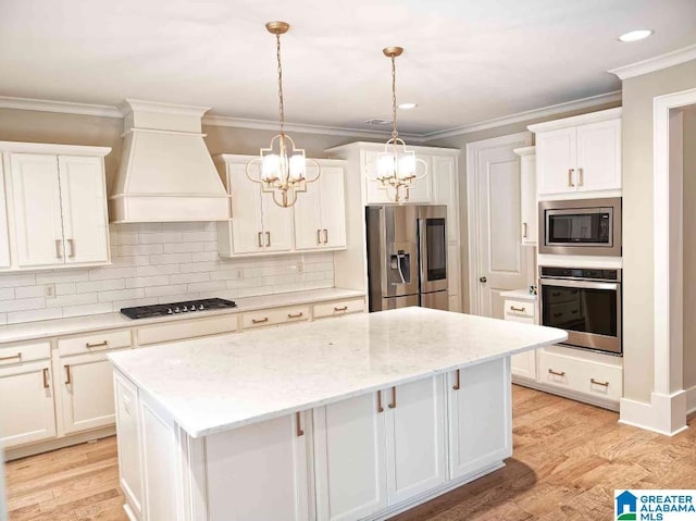 kitchen featuring a kitchen island, white cabinetry, hanging light fixtures, custom exhaust hood, and stainless steel appliances