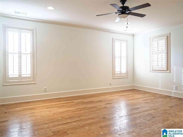 spare room featuring crown molding, a healthy amount of sunlight, and light hardwood / wood-style floors