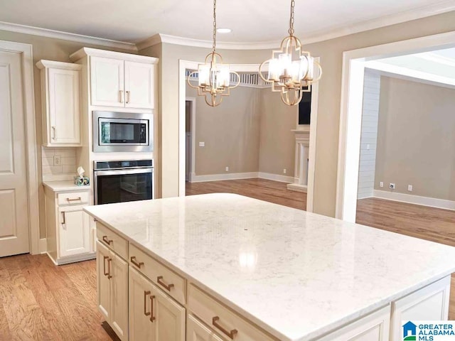 kitchen featuring light stone counters, crown molding, a center island, light wood-type flooring, and appliances with stainless steel finishes