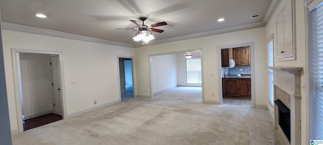 unfurnished living room featuring light colored carpet, ceiling fan, and crown molding