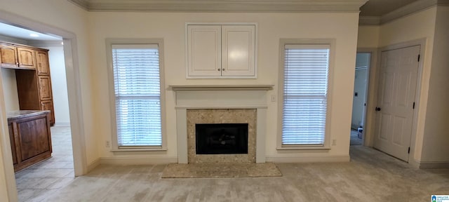 unfurnished living room with light carpet, crown molding, a premium fireplace, and a wealth of natural light