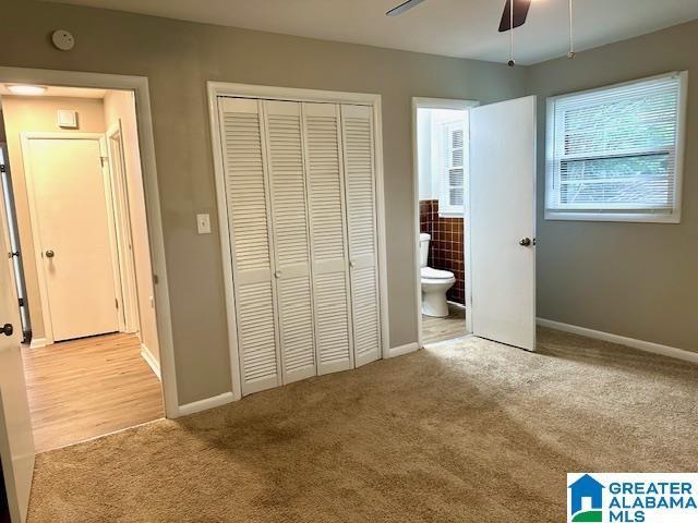 unfurnished bedroom featuring connected bathroom, ceiling fan, a closet, and light colored carpet