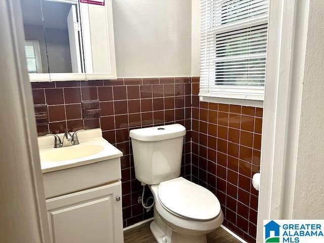 bathroom featuring toilet, vanity, and tile walls