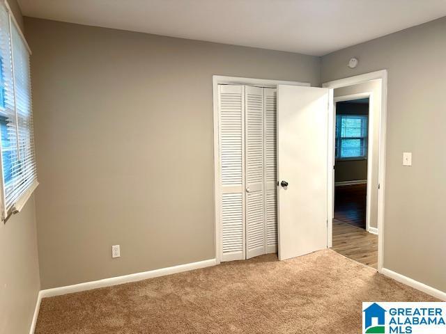 unfurnished bedroom featuring a closet and light carpet