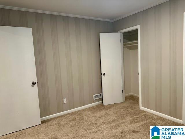 unfurnished bedroom with light carpet, a closet, and ornamental molding