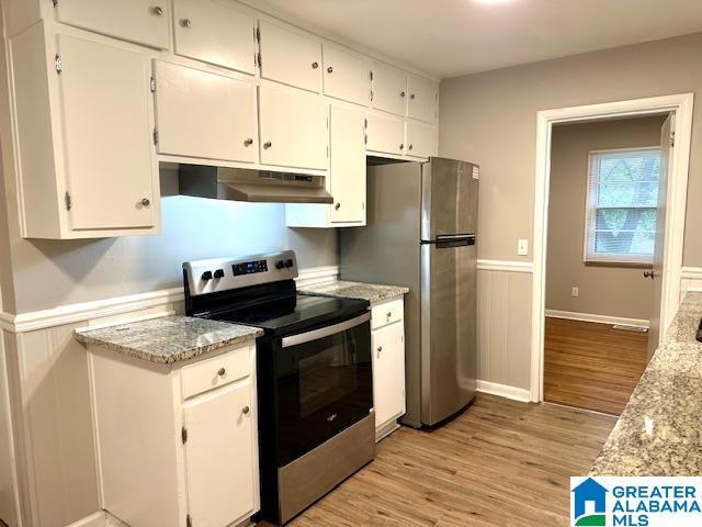 kitchen with light hardwood / wood-style floors, light stone countertops, white cabinets, and stainless steel appliances