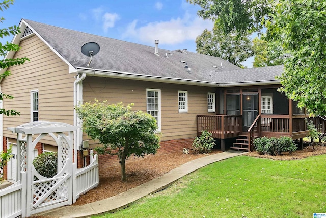 back of property featuring a sunroom and a lawn