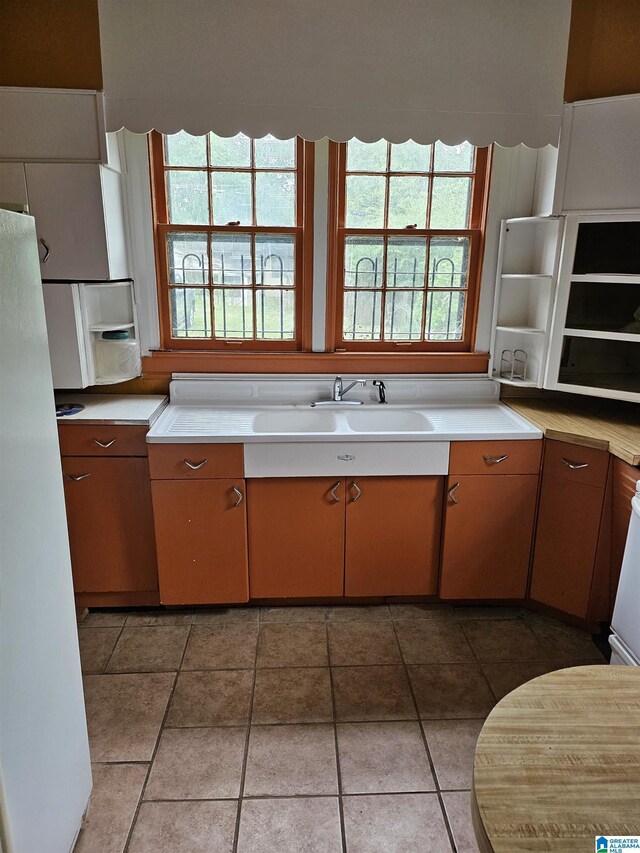 kitchen with tile patterned floors, white refrigerator, and sink