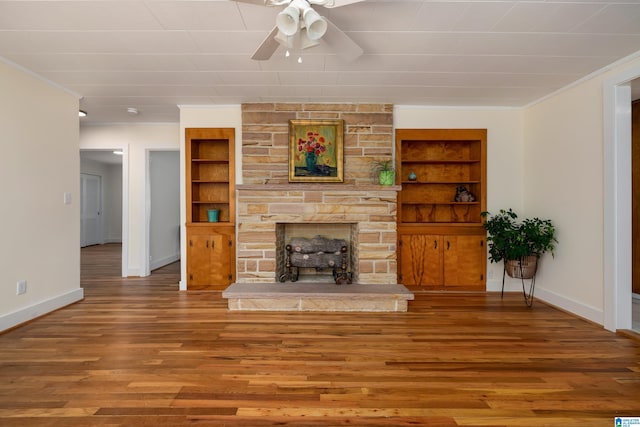 unfurnished living room featuring crown molding, a fireplace, hardwood / wood-style floors, and built in features