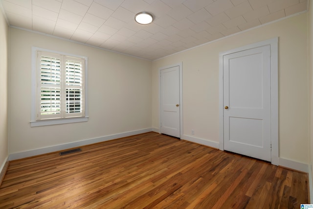 unfurnished bedroom featuring crown molding and dark hardwood / wood-style floors