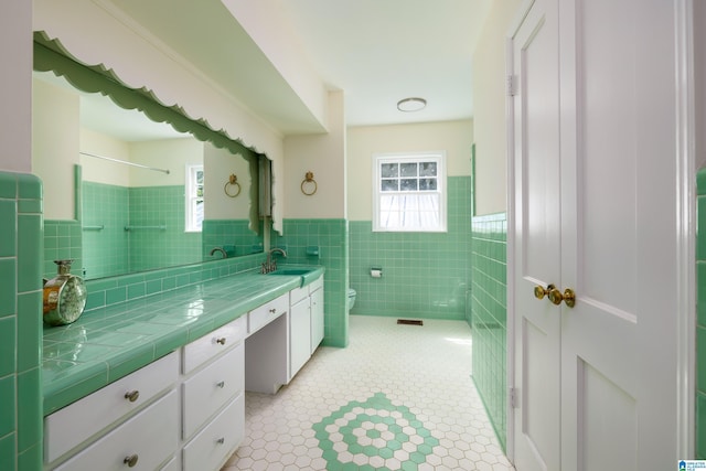 bathroom featuring tile patterned floors, vanity, toilet, and tile walls