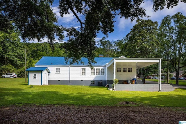 back of property featuring a carport, a yard, central AC unit, and a shed