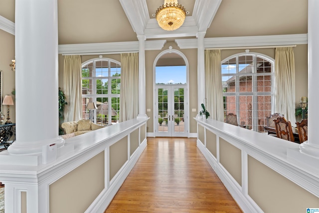 interior space with decorative columns, french doors, light wood-type flooring, and ornamental molding