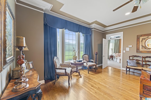 living area featuring crown molding, wood-type flooring, and ceiling fan