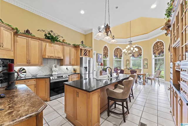 kitchen featuring premium range hood, appliances with stainless steel finishes, pendant lighting, a kitchen island with sink, and decorative backsplash