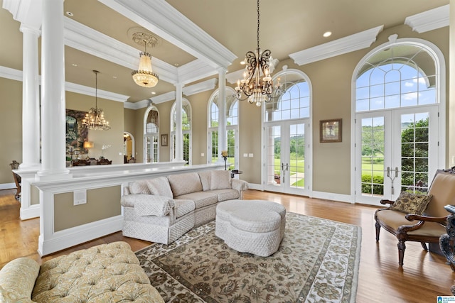 living room with french doors, ornamental molding, an inviting chandelier, and ornate columns