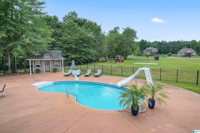 view of pool with a patio, an outdoor structure, a lawn, a playground, and a water slide