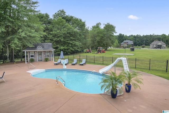 view of swimming pool with a water slide, an outbuilding, a yard, a playground, and a patio