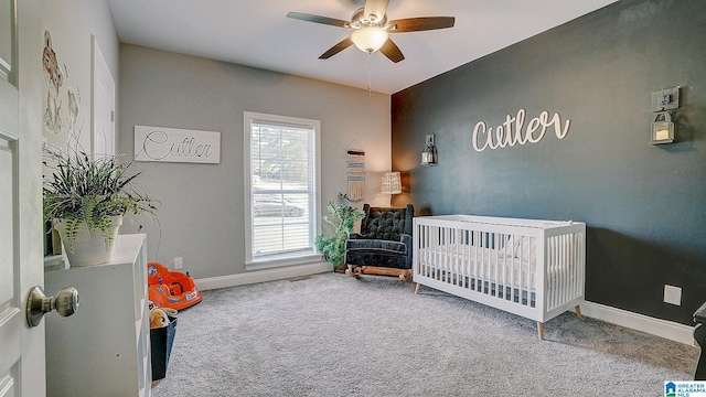 carpeted bedroom featuring multiple windows, a nursery area, and ceiling fan