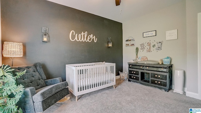 bedroom featuring carpet, a nursery area, and ceiling fan