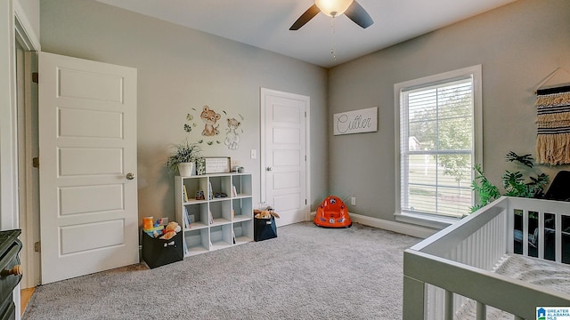 bedroom with a crib, carpet floors, and ceiling fan