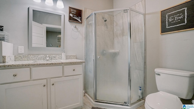 bathroom with a shower with shower door, vanity, and toilet