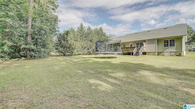 view of yard featuring a trampoline and a deck