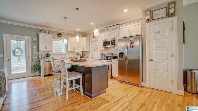 kitchen with appliances with stainless steel finishes, a center island, and light wood-type flooring