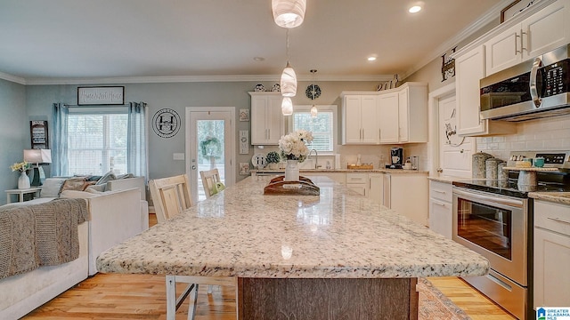 kitchen featuring a center island, appliances with stainless steel finishes, tasteful backsplash, and light hardwood / wood-style floors