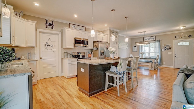 kitchen featuring a center island, appliances with stainless steel finishes, light wood-type flooring, and white cabinets