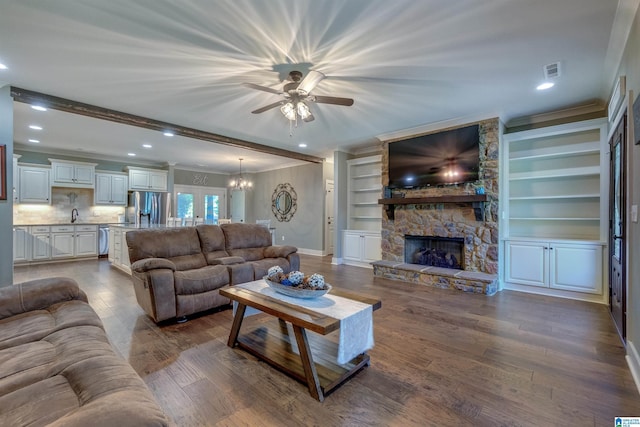 living room featuring a stone fireplace, dark hardwood / wood-style floors, ornamental molding, beam ceiling, and built in shelves