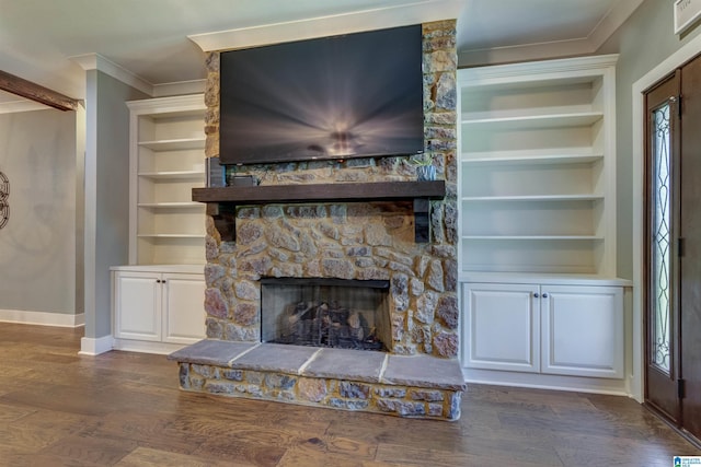 unfurnished living room with crown molding, a stone fireplace, dark wood-type flooring, and built in shelves