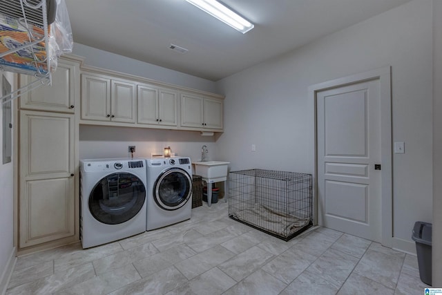 washroom featuring cabinets, washing machine and dryer, and sink