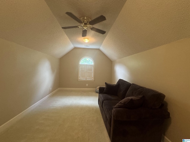 interior space with ceiling fan, light colored carpet, a textured ceiling, and lofted ceiling
