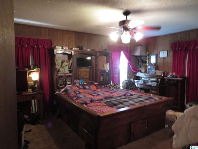 bedroom featuring a textured ceiling, wooden walls, and ceiling fan