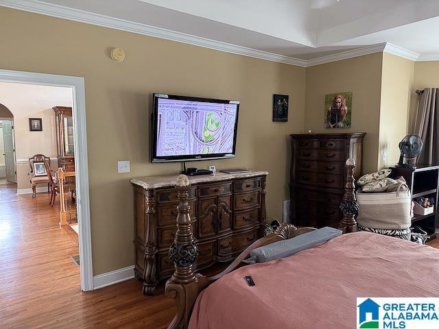 bedroom with light hardwood / wood-style floors, a tray ceiling, and crown molding