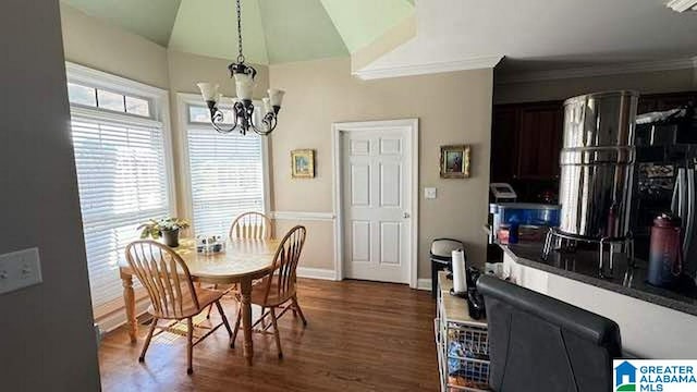 dining room with dark wood-type flooring, vaulted ceiling, a notable chandelier, and crown molding