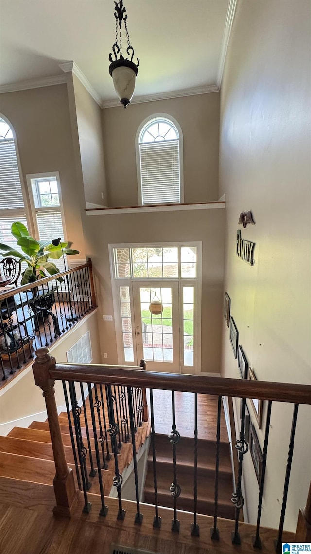 staircase with a towering ceiling, crown molding, and hardwood / wood-style floors