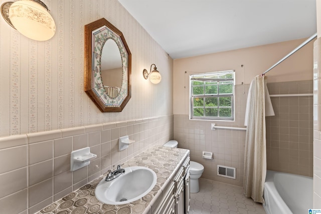 full bathroom with toilet, shower / tub combo, tile walls, vanity, and tile patterned flooring