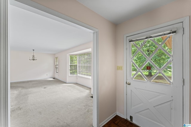 doorway featuring a chandelier and dark carpet