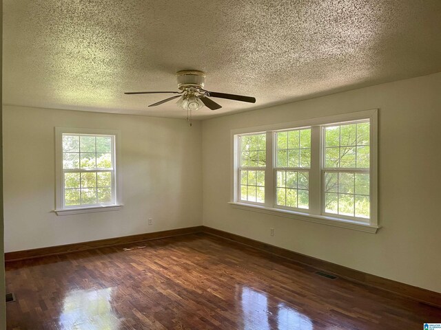 empty room with ceiling fan, dark hardwood / wood-style flooring, and a wealth of natural light