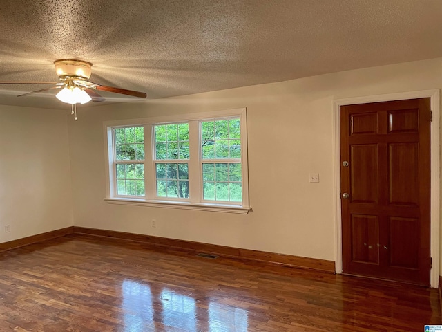 unfurnished room with dark wood-style floors, a textured ceiling, visible vents, and baseboards