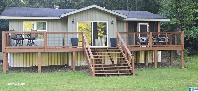 rear view of property featuring a lawn and a deck